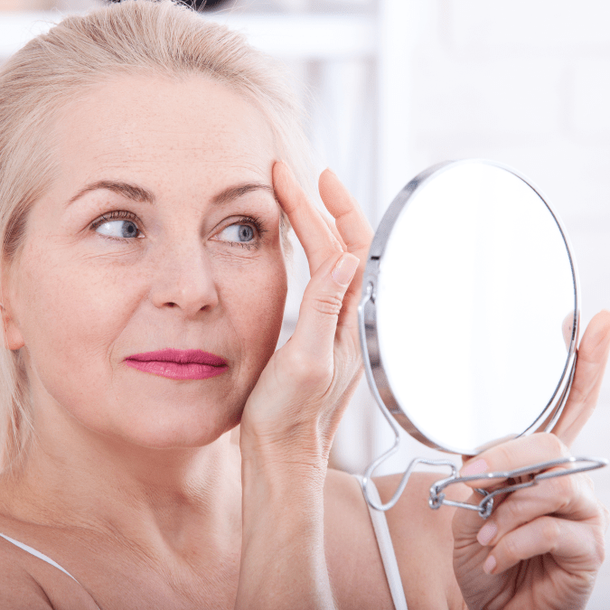 woman looking herself in a hand mirror